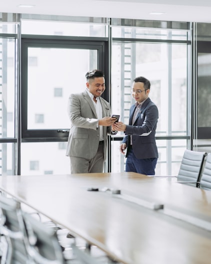 two businessmen smiling looking at a phone